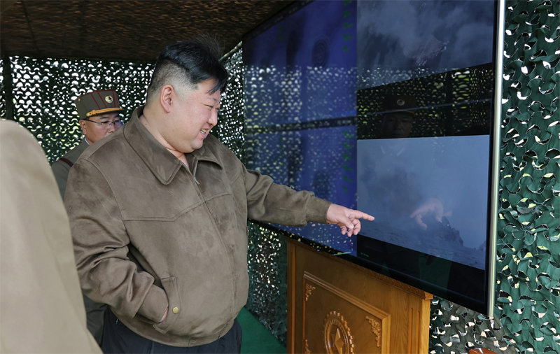 김정은 국무위원장이 22일 600mm 초대형 방사포 발사 훈련을 보여주는 모니터 화면을 손으로 가리키고 있다.  노동신문 뉴스1