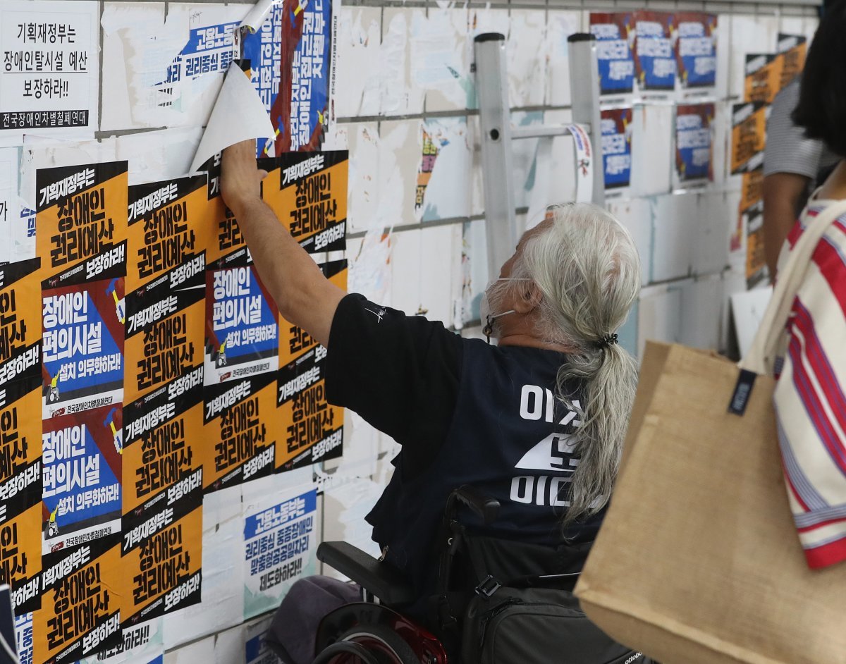 전국장애인철폐연대 박경석 공동대표가 3일 오전 서울 지하철 4호선 삼각지역에서 자신들의 요구가 적힌 스티커가 떼어지자 그 위에 스티커를 덧붙이고 있다. . 2022.8.3.뉴스1