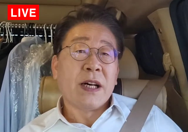 이재명 대표가 23일 노무현 전 대통령 추도식 참석을 위해 경남 김해 봉하마을로 이동하는 차 안에서 라이브 유튜브 방송을 하며 “현재 2만 명 넘게 탈당했다”고 말하고 있다. 유튜브 화면 캡처