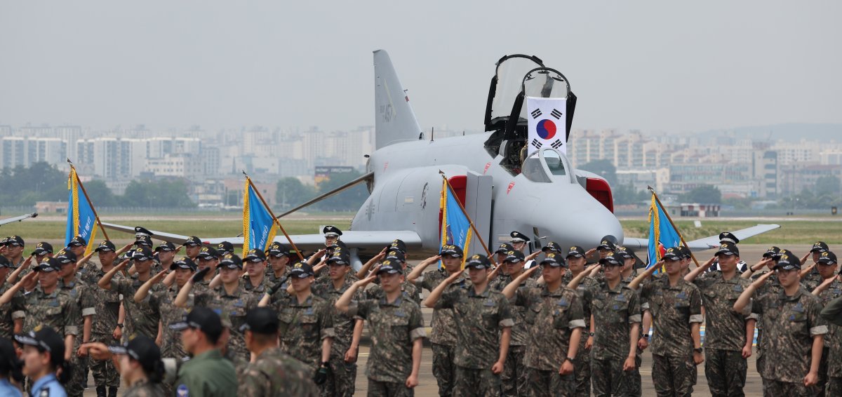 5일 경기 수원 공군 제10전투비행단에서 장병들이 비행을 마치고 퇴역을 앞둔 F-4 팬텀 전투기를 향해 경례를 하고 있다. 장병들 뒤로 이미 퇴역한 F-4 팬텀 전투기가 보인다. 수원=뉴시스