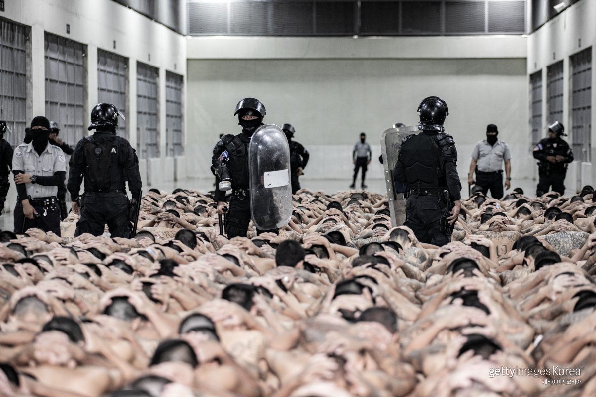 수감자들이 머리에 손깍지를 낀 채 테러범수용센터 바닥에 앉은 모습. (엘살바도르 대통령실 제공) ⓒ(GettyImages)/코리아