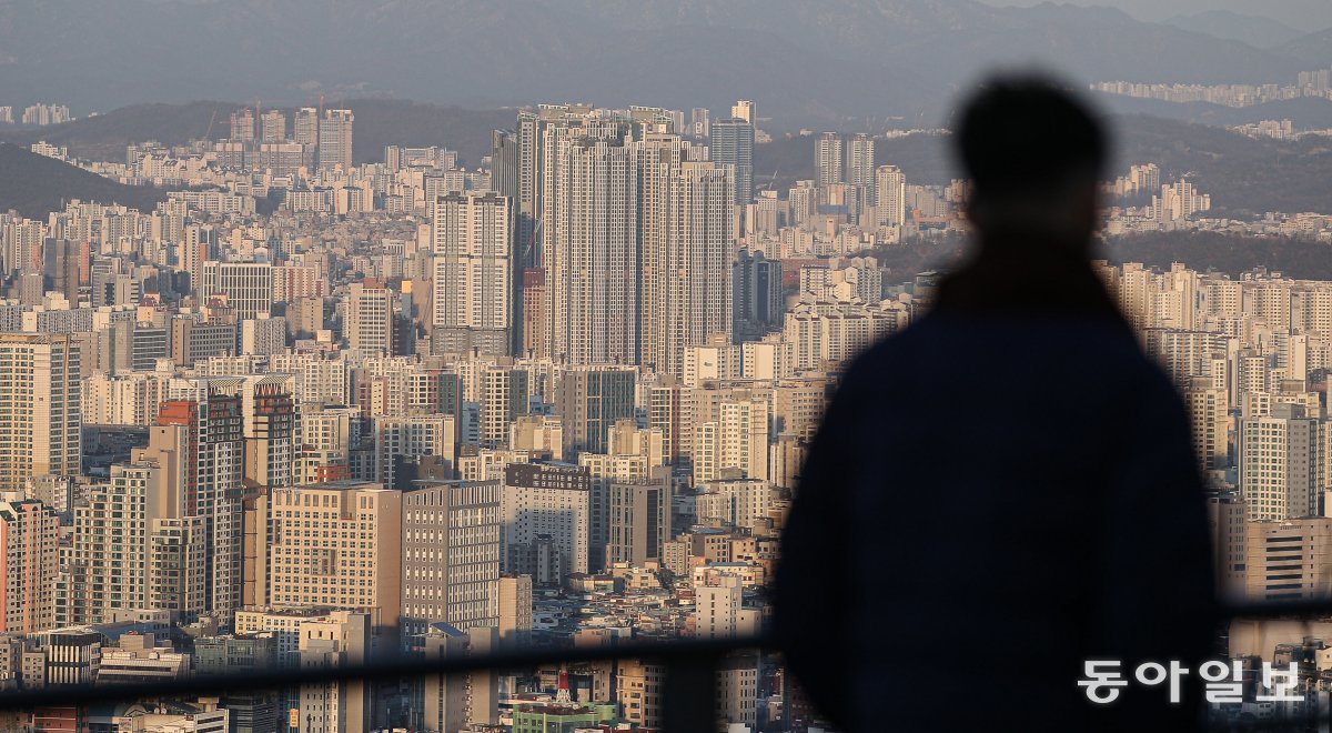 The government plans to continue to enforce strict regulations on speculative real estate transactions by foreigners.  However, experts' reactions to this are somewhat mixed.  The photo shows a citizen looking down at apartments in the city from Namsan Mountain in Seoul.  Donga Ilbo DB