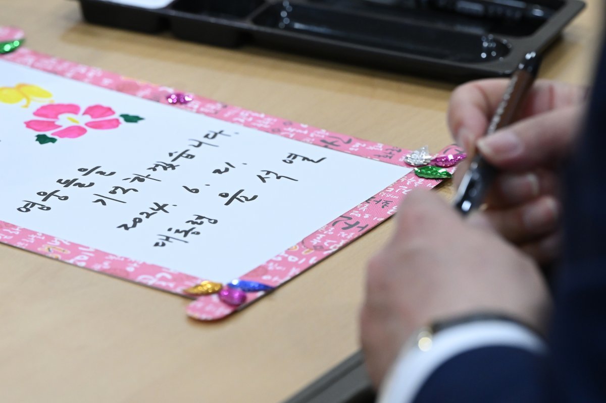 President Yoon Seok-yeol visits the Suwon Veterans Nursing Home in Gyeonggi Province on the 21st and writes a message of encouragement to a person of national merit in a frame expressing his love for the country.  2024.6.21/Provided by Presidential Office