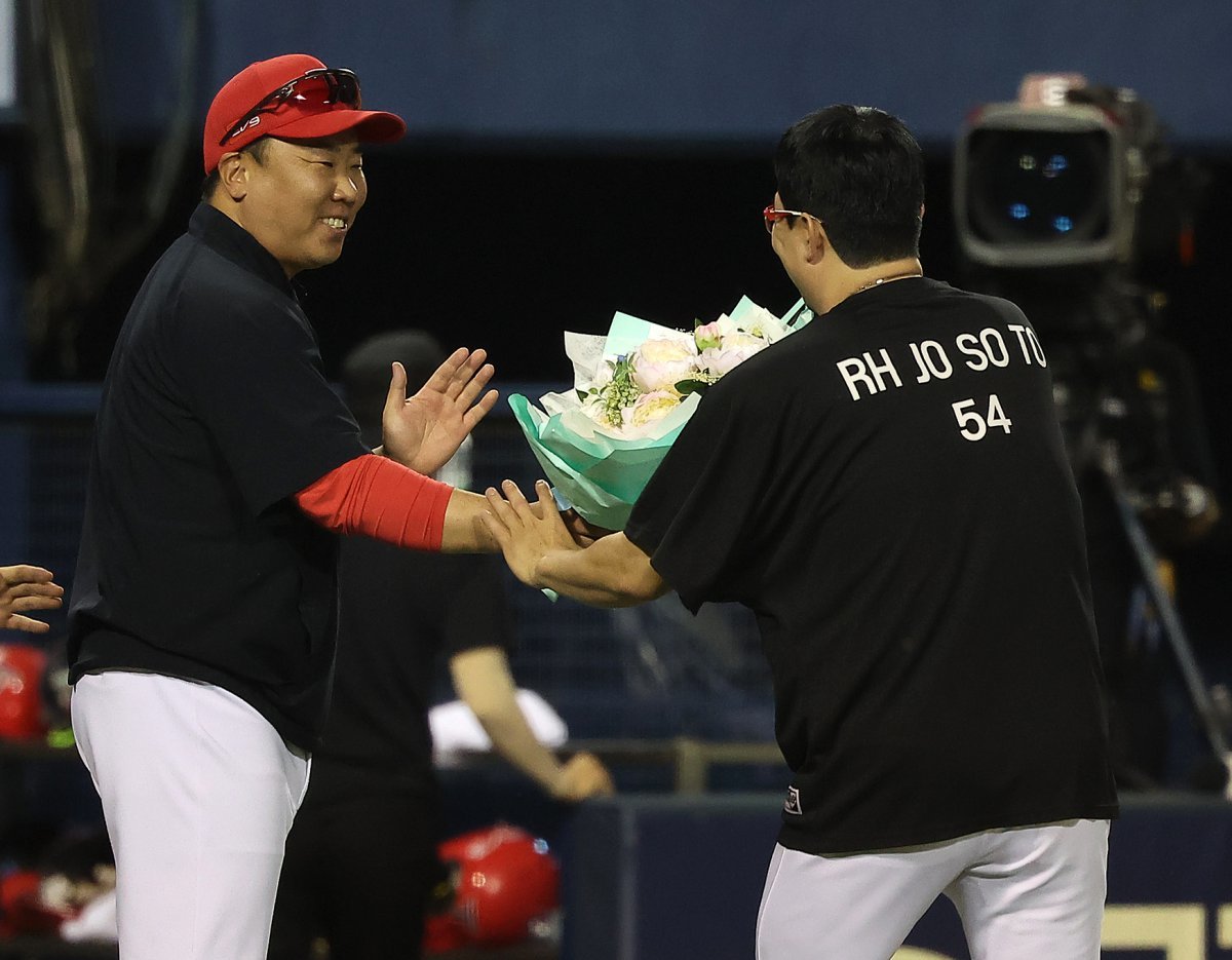 10일 오후 서울 송파구 잠실야구장에서 열린 프로야구 ‘2024 신한 SOL 뱅크 KBO리그’ KIA 타이거즈와 LG 트윈스의 경기, 5대2 승리를 거둔 KIA 이범호 감독이 이날 선발 등판으로 KBO리그 최초로 400경기 등판 신기록과 함께 4회말 선두 타자 오스틴 딘을 투수 직선타로 잡아내 올 시즌 100이닝을 채우면서 역대 3번째로 11시즌 연속 100이닝 기록을 세운 양현종에게 꽃다발을 전달하고 있다. 2024.7.10 뉴스1