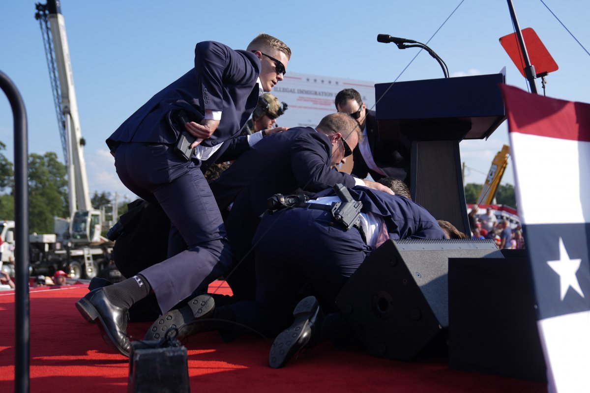 A photographer taking pictures just below the podium ran to the right of the podium after hearing gunfire and captured Trump surrounded by security guards (AP Photo/Evan Vucci)