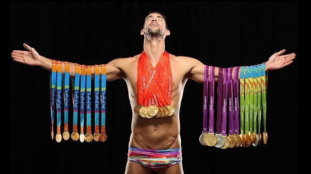 Michael Phelps poses with his Olympic medal. Photo courtesy of Sports Illustrated (SI) website.