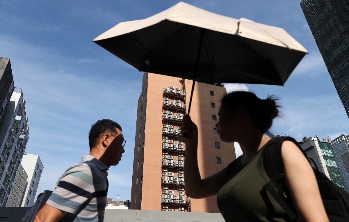 8일 서울 종로구의 에어컨실외기가 밀집된 한 건물외벽 앞으로 양산을 쓴 한 시민이 지나가고 있다. 2024.8.8. 뉴스1