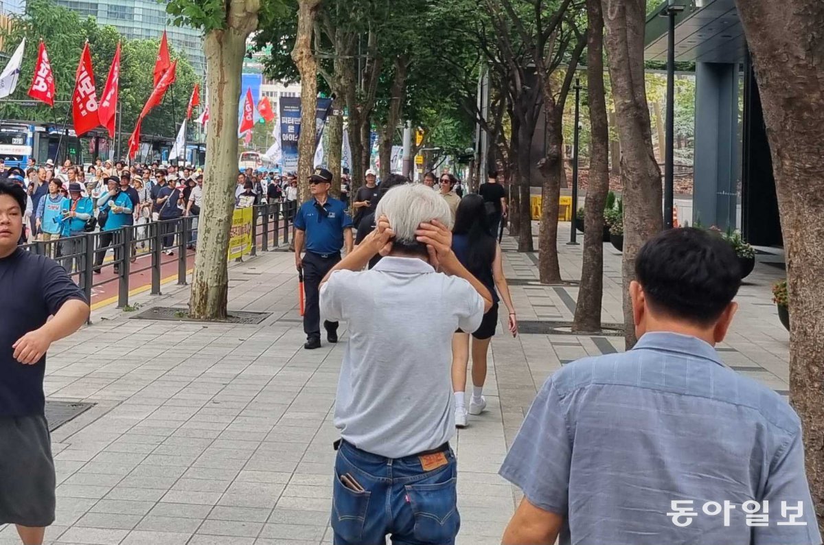 10일 오후 4시  반경 서울 광화문 시내를 행진하는 시위대 옆을 한 시민이 양쪽 귀를 막은 채 지나고 있다. 주현우 기자 woojoo@donga.com