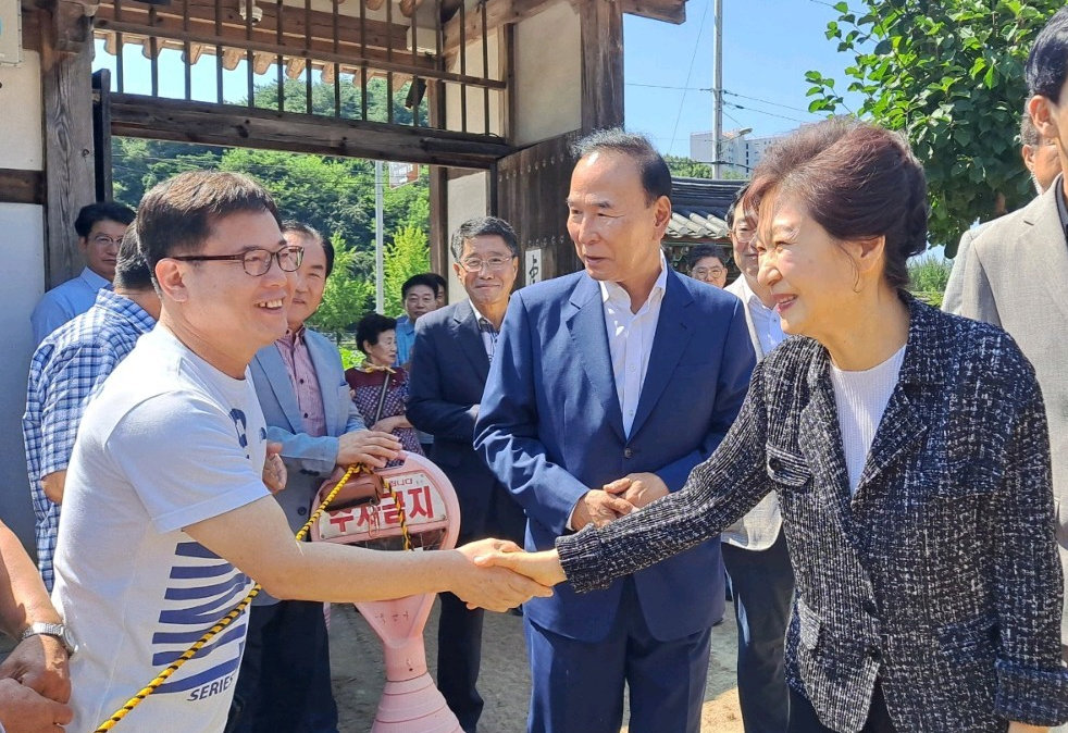 박근혜 전 대통령(오른쪽)이 14일 충북 옥천에 있는 어머니 고 육영수 여사 생가를 방문해 주민과 악수를 나누고 있다. 옥천이 지역구인 국민의힘 박덕흠 의원(가운데)과 유영하 의원 등이 동행했다. 옥천=뉴스1