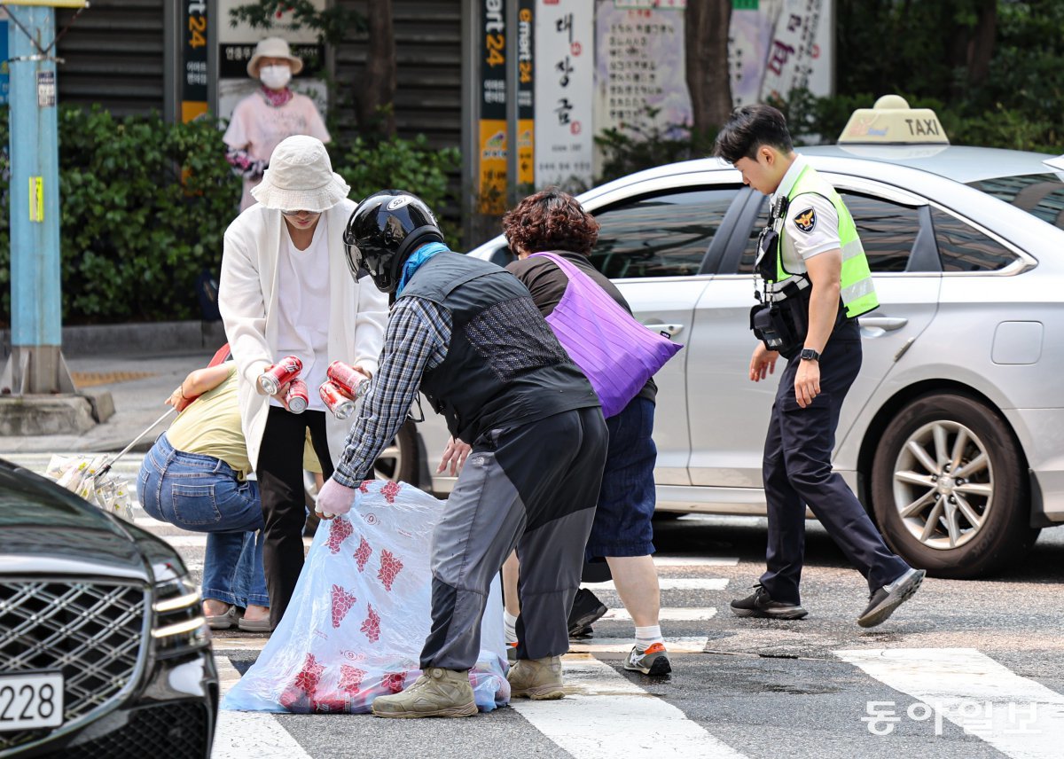 16일 오전 서울 종로구 서울경찰청 앞 사거리에서 탄산음료 캔 수백 개가 쏟아져 시민들과 한 경찰이 배송 기사를 도와 거리를 치우고 있다. 이한결 기자 always@donga.com