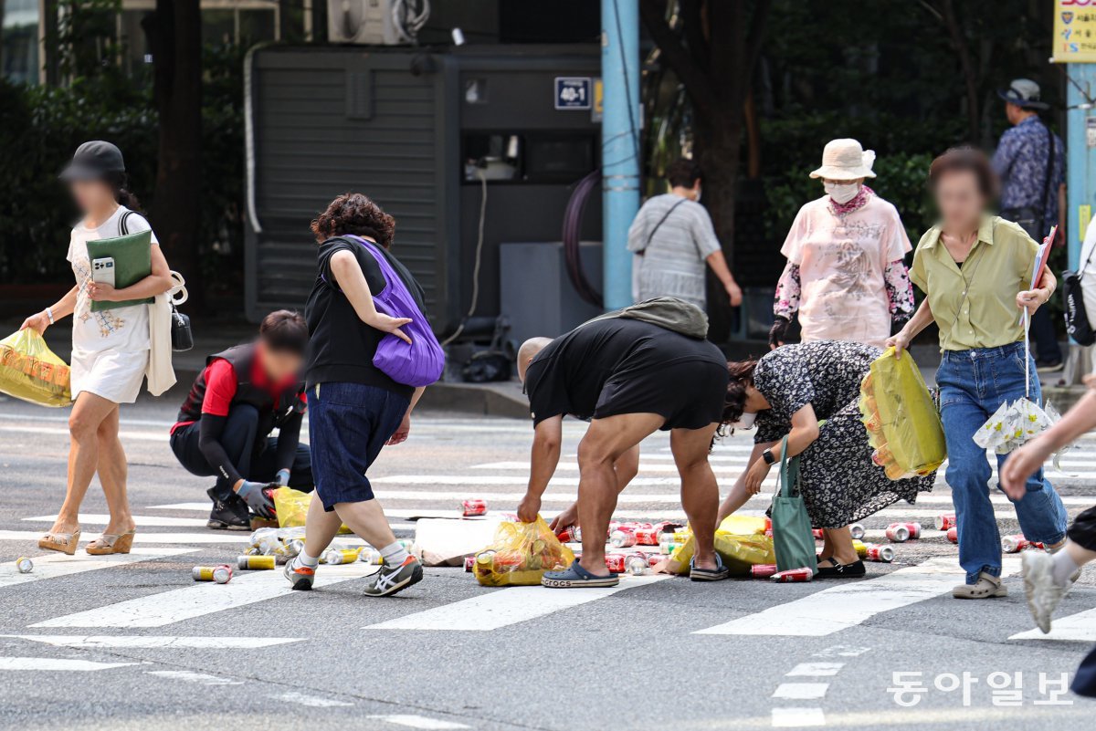 16일 오전 서울 종로구 서울경찰청 앞 사거리에서 탄산음료 캔 수백 개가 쏟아져 시민들이 배송 기사를 도와 거리를 치우고 있다. 이한결 기자 always@donga.com