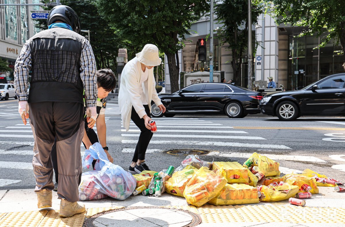 16일 오전 서울 종로구 서울경찰청 앞 사거리에서 탄산음료 캔 수백 개가 쏟아져 시민들이 배송 기사를 도와 거리를 치우고 있다. 이한결 기자 always@donga.com