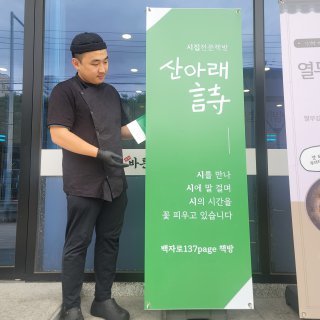 산아래시 2호점의 간판 옆에 선 김민석 씨. 돼지국밥 프랜차이즈 식당 한켠에 책방을 차렸다. 김민석 씨 제공