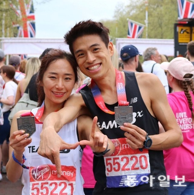 Ms. Mok Young-ju (left) poses with her finisher's medal after running the 2018 London Marathon with her husband, Mr. Lee Byeong-do. Courtesy of Ms. Mok Young-ju.