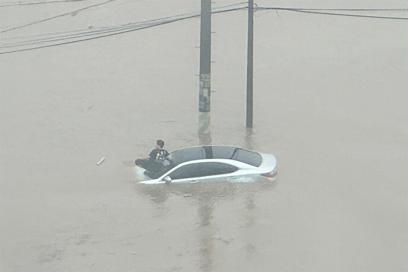 車 위 고립된 주민 21일 호우특보가 발효된 경남 김해시에서 한 남성이 보닛까지 잠긴 차량의 앞 유리창 위로 대피해 있다. 사진 출처 ‘X’