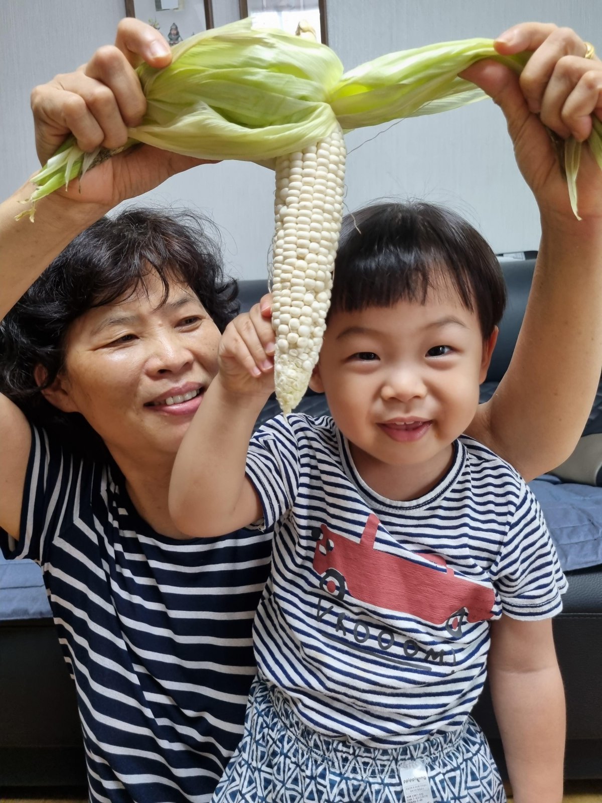 서울시가 이달 선정한 ‘서울형 아이 돌봄비’ 사업 시행 1주년 기념 공모전 수상작. 전화순 씨가 손자 김진규 군과 함께 옥수수를 손에 들고 웃고 있다. 서울시 제공