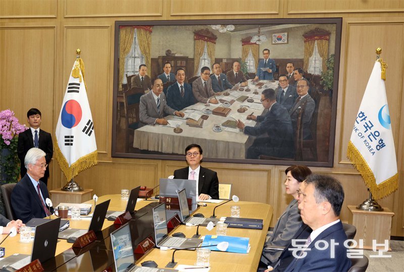 이창용 한국은행 총재(가운데)가 서울 중구 한국은행에서 금융통화위원회를 주재하는 모습. 회의실 벽면에 김태 작가의 그림 ‘1950년 6월 5일 제1차 ‘금융통화위원회’(330×220cm, 1987년)가 걸려 있다. 최순주 전 재무부 장관을 비롯한 13명이 마치 시공을 넘어 현재 회의에 참석하는 듯한 효과를 자아내 금통위의 전통과 권위를 강조한다. 동아일보DB