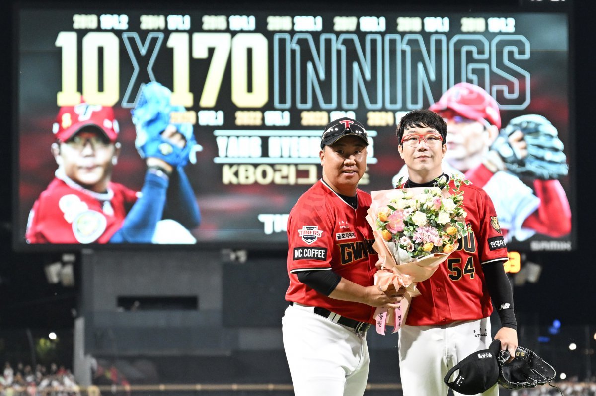 10년 연속 170이닝 이상 소화한 KIA 양현종(오른쪽)과 축하 꽃다발을 건네는 이범호 감독. 광주=뉴시스