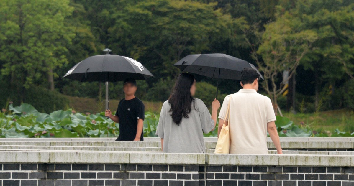 전국적으로 선선한 날씨가 이어지고 있는 20일 전북 전주시 전주덕진공원을 찾은 시민들이 우산으로 비를 피하며 길을 지나고 있다. 2024.09.20. 뉴시스