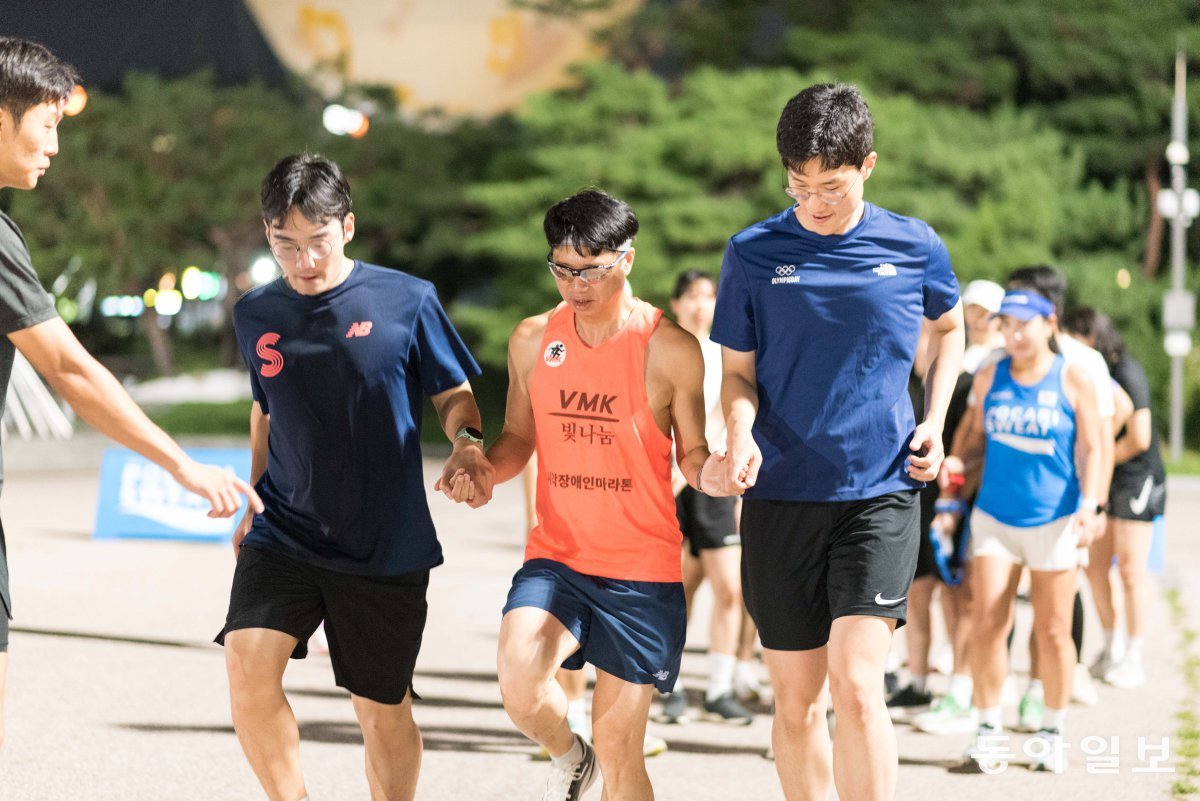 지난달 서울 영등포구 여의도공원 문화의 마당에서 ‘가이드 러닝 클래스’ 프로그램에 참여한 시민들이 시각장애인의 손을 잡고 함께 달리는 동작을 연습하고 있다. 서울시 제공