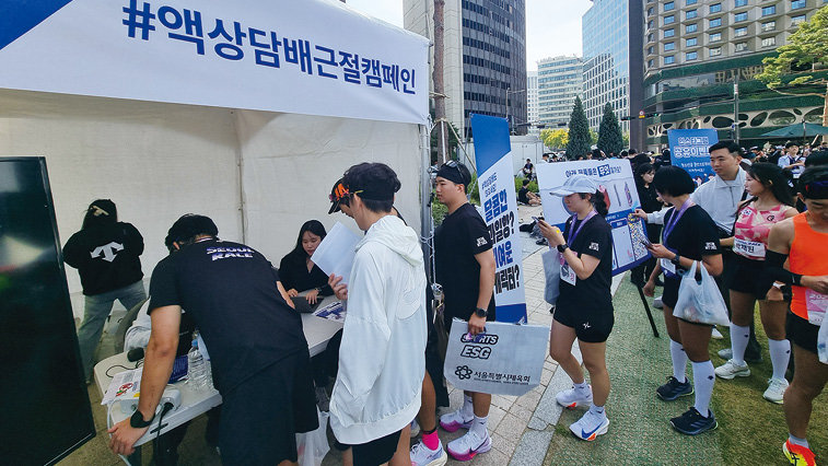 지난달 13일 서울광장에서 열린 서울달리기 행사 참가자들이 ‘액상 담배 근절 캠페인’ 부스를 찾아 이벤트에 참여하고 있다. 서울달리기 사무국 제공