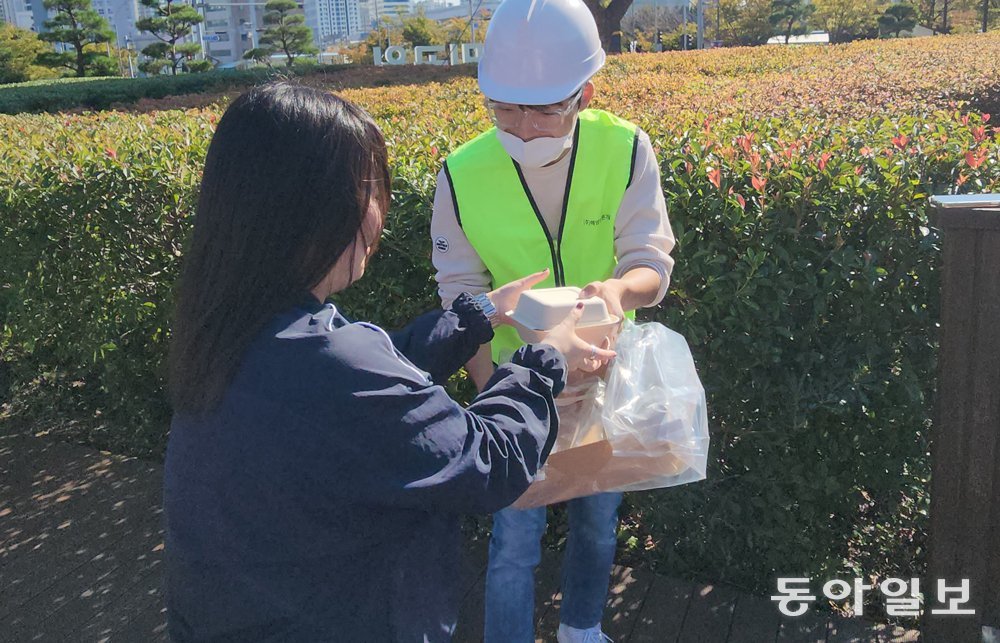 지난달 25일 부산 부산진구 부산시민공원 음악분수에서 한 시민이 드론으로 배송된 음식물을 전달받고 있다. 김화영 기자 run@donga.com