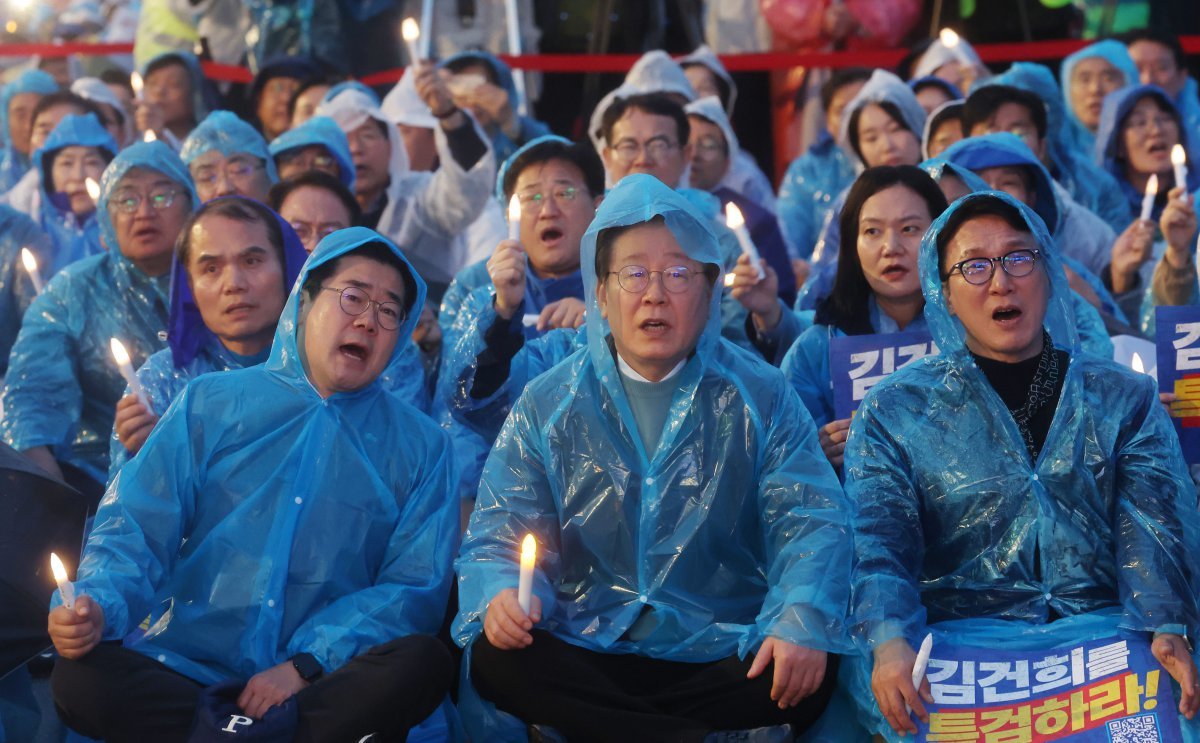 16일 저녁 광화문광장 앞 도로에서 열린 ‘김건희·윤석열 국정농단 규탄·특검 촉구 제3차 국민행동의 날 및 시민사회 연대 집회’에서 더불어민주당 박찬대 원내대표, 이재명 대표, 김민석 최고위원(앞 줄 왼쪽부터)이우비를 입은 채 손에 촛불을 들고 구호를 외치고 있다. 뉴스1