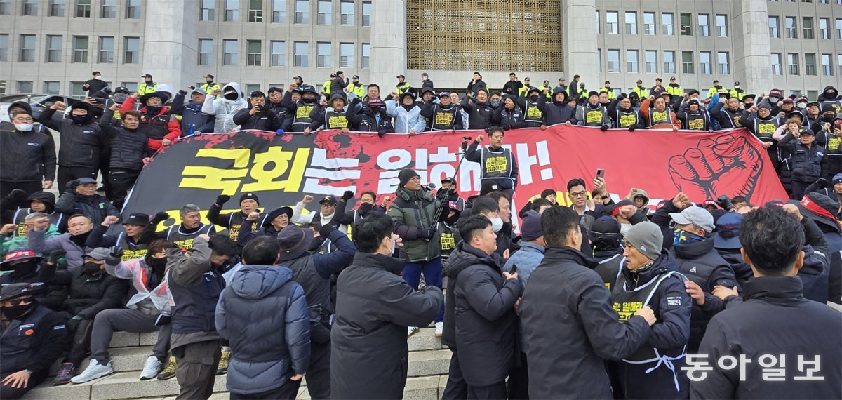 화물연대 조합원 국회서 기습시위 26일 오후 전국민주노동조합총연맹(민노총) 공공운수노조 화물연대본부 조합원들이 서울 여의도 국회 본청 앞 계단에서 안전운임제 입법을 촉구하며 기습시위를 하고 있다. 민노총 공공운수노조는 이날 서울 용산구 대통령실 앞에서 기자회견을 열고 공공부문 공동 파업에 돌입한다고 밝혔다. 철도, 화물, 학교, 공기업 부문 산하 노조들이 참여하는 이번 파업은 12월 첫 주에 연쇄적으로 진행될 예정이다. 이훈구 기자 ufo@donga.com