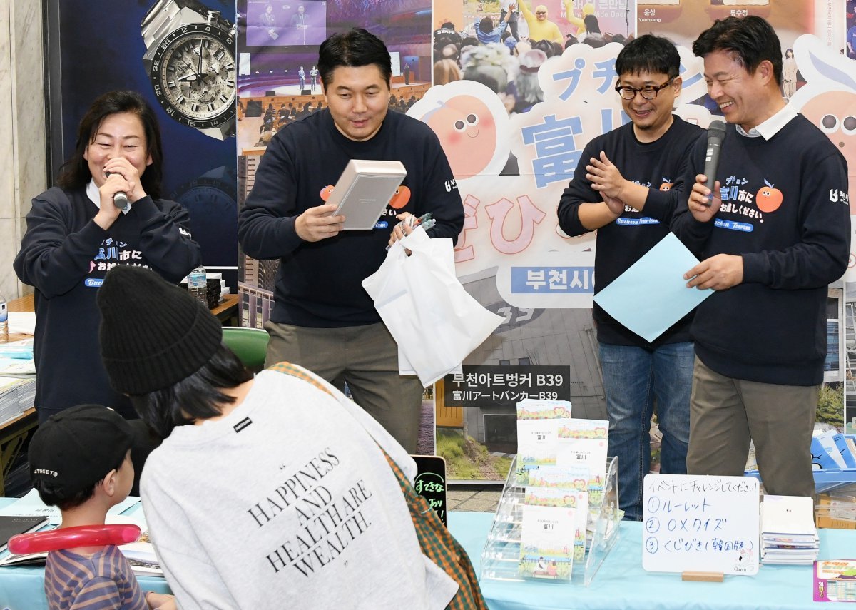 조용익 부천시장(오른쪽)이 일본 오카야마시 상점가에서 부천의 주요 문화축제를 소개하며 환하게 웃고 있다. 두 도시는 관광시설을 서로 할인된 가격으로 시민들이 이용하는 업무협약(MOU)을 맺었다. 부천시 제공