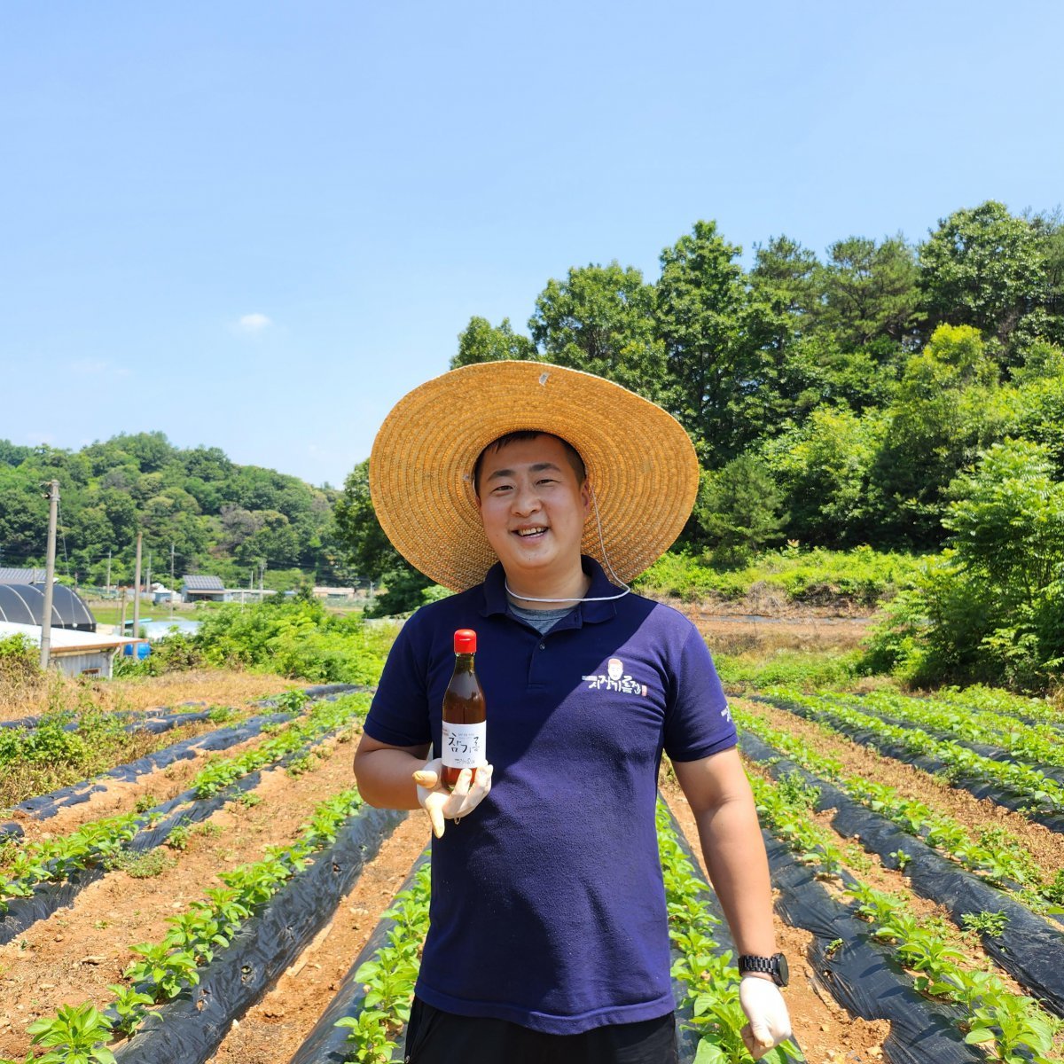 정승준 시장기름집 대표는 ‘우리 손을 거치지 않은 제품은 절대 팔지 않는다’는 원칙을 갖고 참깨도 직접 재배한다. 정 대표가 자신의 참깨밭에서 판매 중인 참기름을 들고 있는 모습. 소상공인시장진흥공단 제공