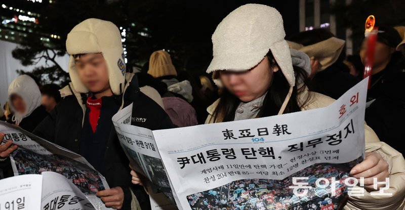 윤석열 대통령 탄핵소추안이 국회 본회의를 통과한 14일 오후 여의도 국회 앞에 모인 시민들이 동아일보 호외를 읽고 있다. ‘호외’라는 글자와 ‘尹대통령 탄핵, 직무정지’라는 헤드라인이 보인다. 송은석 기자 silverstone@donga.com