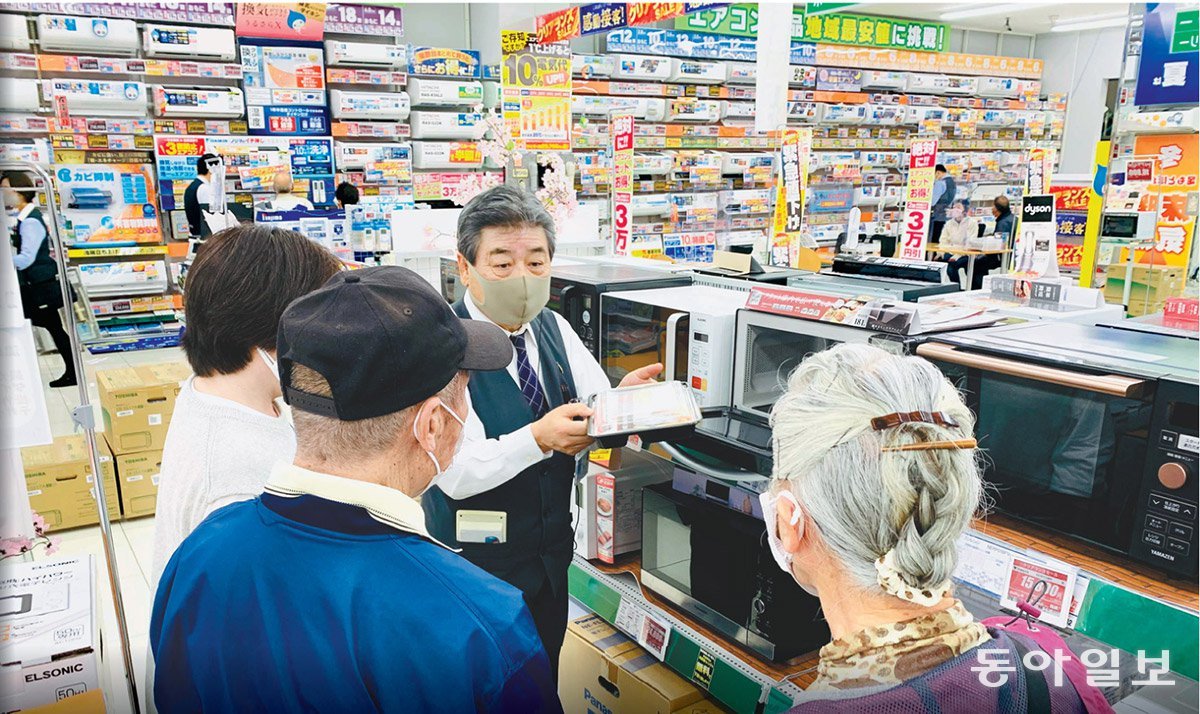 73세 판매 사원인 사토 다다시 씨(왼쪽에서 세 번째)가 가나가와현 후지사와시의  ‘노지마’ 가전 매장에서 고객들에게 전자레인지의 성능에 대해 설명하고 있다. 동아일보 DB