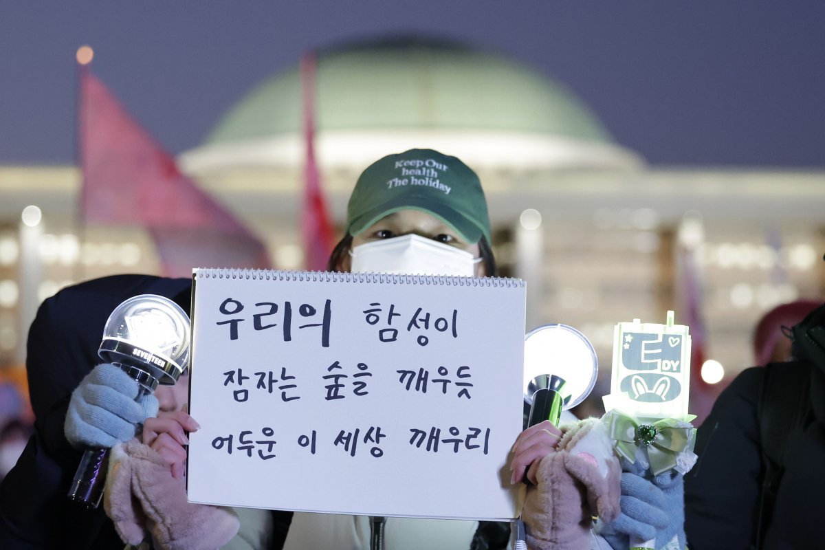 윤석열 대통령 탄핵안이 가결된 14일 서울 영등포구 국회 앞에서 열린 촛불집회 참가자가 손글씨 메시지를 적은 스케치북을 들어 보이고 있다. 뉴시스