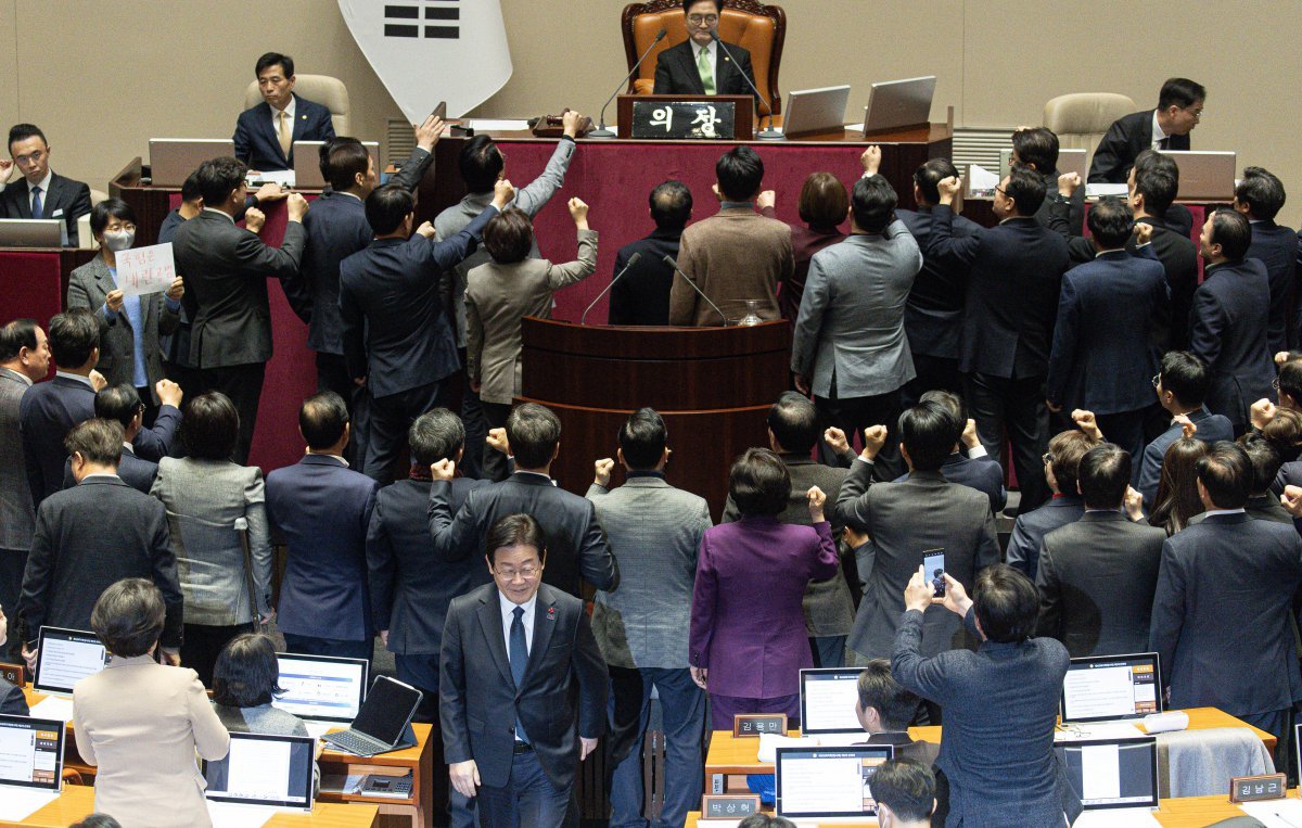 우원식 국회의장이 27일 오후 국회 본회의에서 한덕수 대통령 권한대행 탄핵소추안 가결 정족수를 ‘재적 의원 과반(151명) 찬성’이라고 밝히자 국민의힘 의원들은 의장석 앞으로 몰려가 “원천 무효”라고 외치며 항의하고 있다. 그 뒤로 더불어민주당 이재명 대표가 탄핵안 투표를 마친 뒤 자리로 향하고 있다. 뉴스1