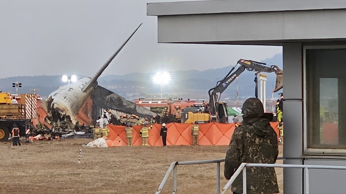 29일 오후 전남 무안군 무안국제공항에서 제주항공 여객기 추락 참사와 관련해 소방 당국이 잔해 더미 수색 작업을 벌이고 있다. 공항 내 공군 소속 초병이 수색 작업을 바라보고 있다. 2024.12.29 무안=뉴시스