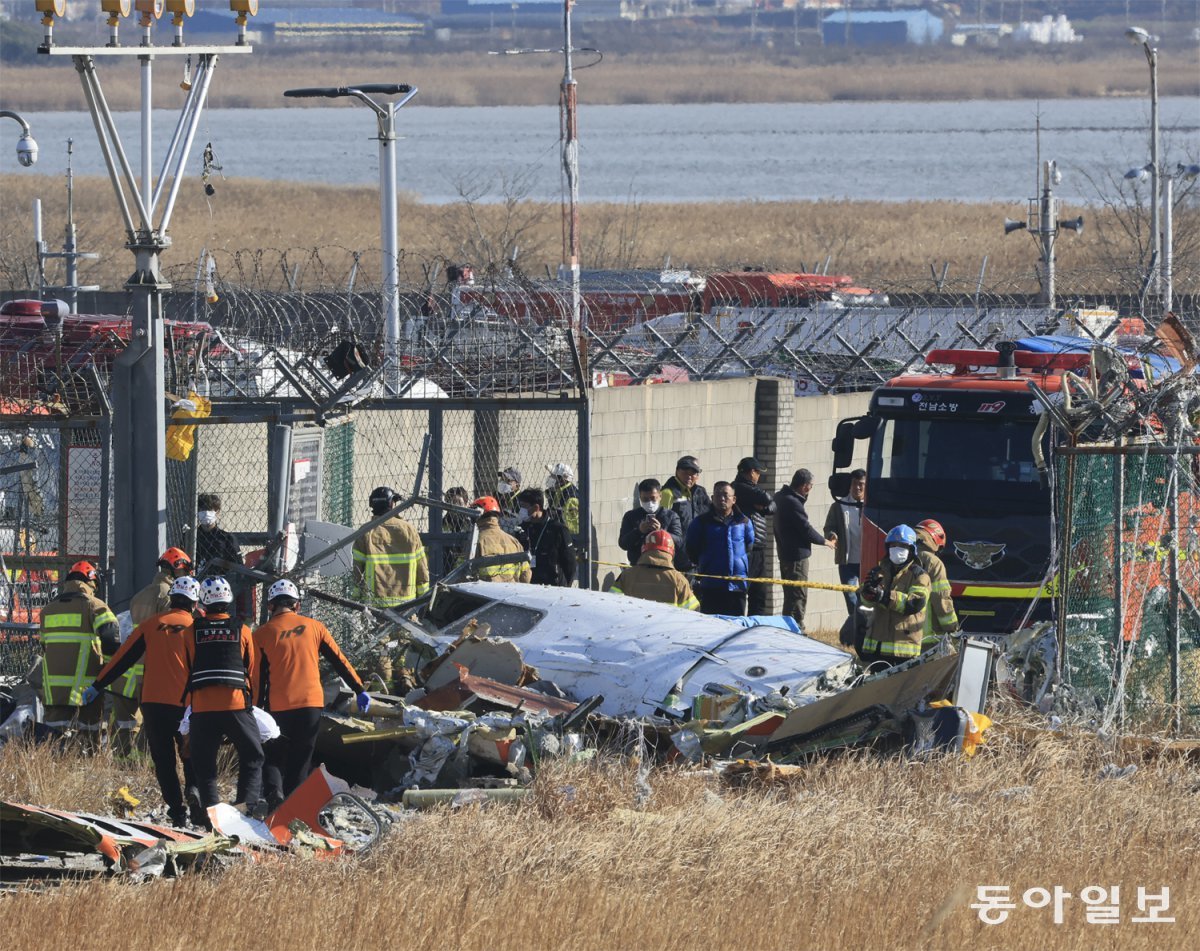 소방당국 등 사고 수습 관계자들이 29일 오전 전남 무안국제공항 착륙 도중 활주로 외벽과 충돌해 크게 파손된 제주항공 여객기의 조종석으로 추정되는 동체 주변을 수색하고 있다. 무안=박영철 기자 skyblue@donga.com