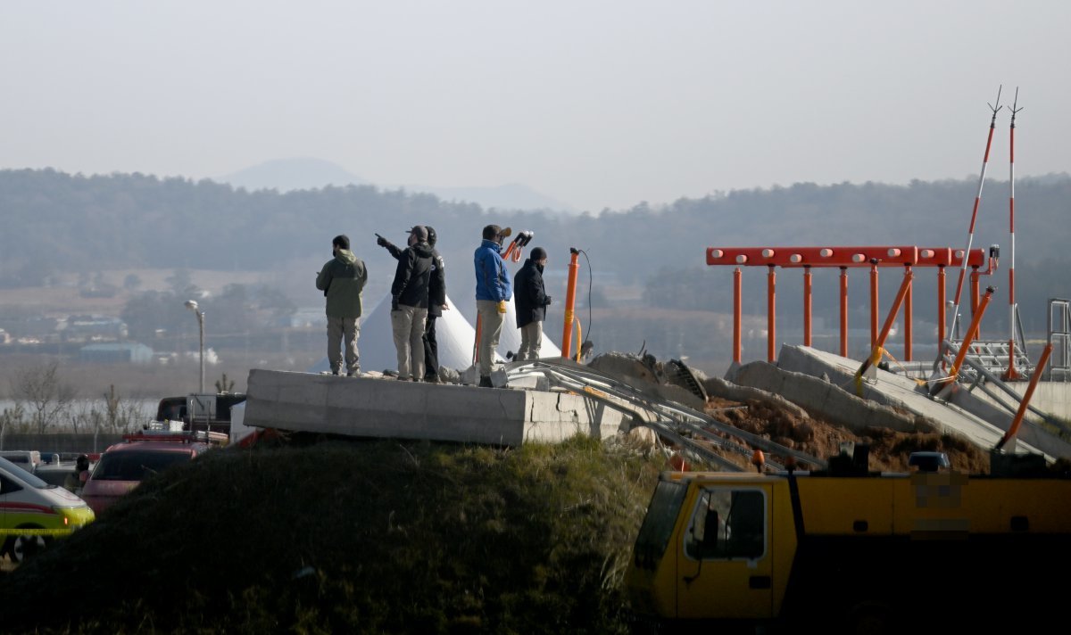 1일 오전 전남 무안국제공항에서 항공철도사고조사위원회와 미국합동조사관이 여객기와 충돌한 둔덕의 콘크리트 상판 위에 올라가 조사하고 있다. 그 옆에 주황색 착륙유도 조명시설과 붉은색과 하얀색으로 된 이쑤시개 모양의 로컬라이저 안테나가 보인다. 무안=뉴시스