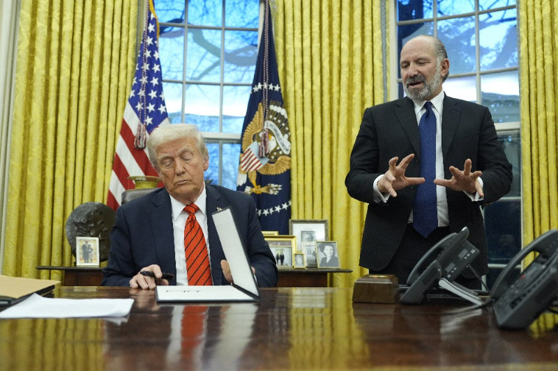 President Donald Trump signs an executive order in the Oval Office at the White House, Monday, Feb. 10, 2025, in Washington, as Commerce Secretary nominee Howard Lutnick talks. (Photo/Alex Brandon)