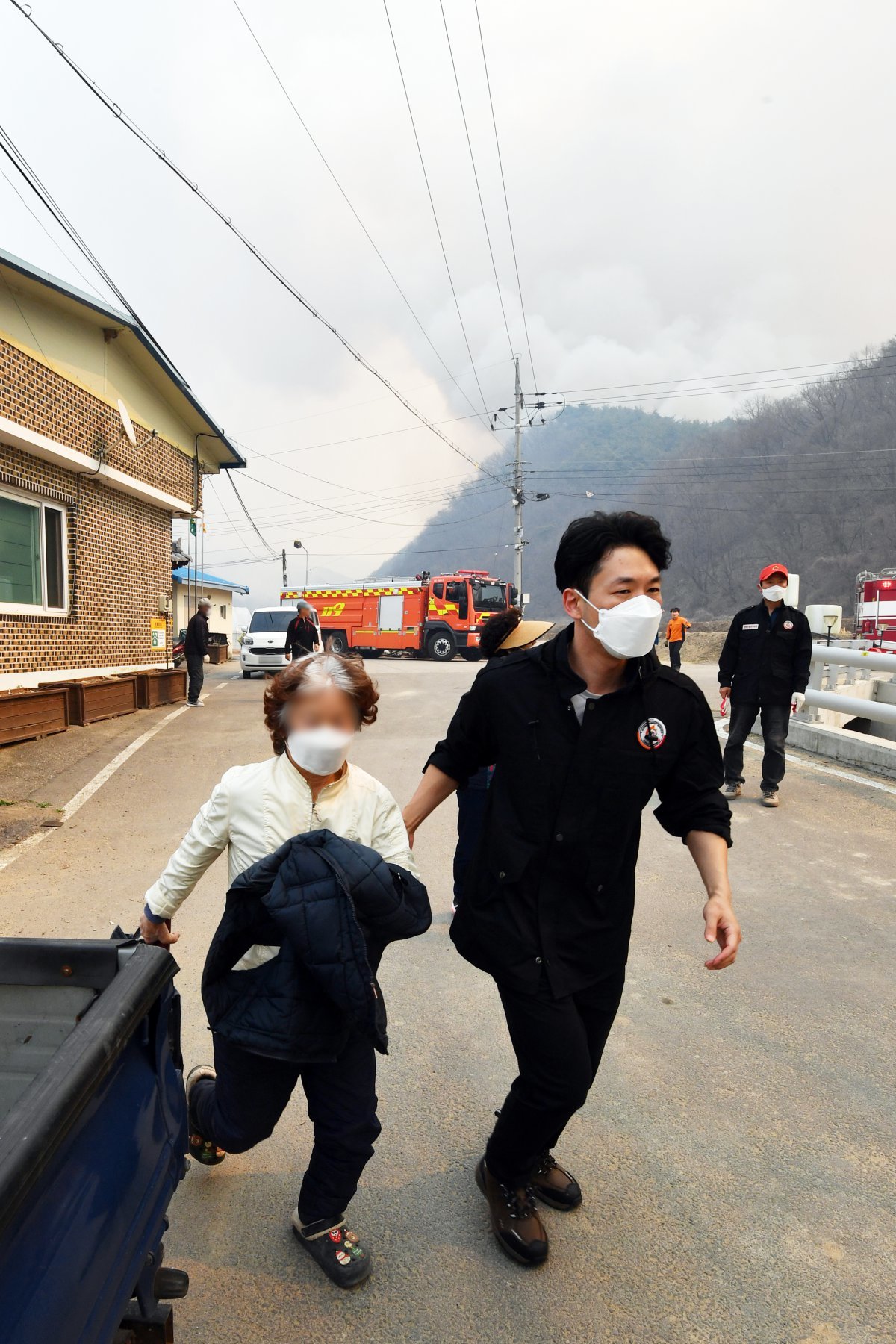 경북 의성군 산불 이틀째인 23일 오후 단촌면 상화리 주민들이 마을 앞까지 불길이 확산되자 안전한 곳으로 대피하고 있다. 뉴스1