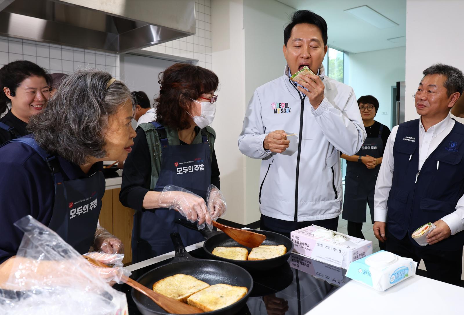 오세훈 서울시장이 14일 오후 서울 중구 해든센터에서 열린 남대문 쪽방촌 임대주택 ‘해든집’ 입주 축하 행사에 참석해 공유주방에서 요리교실 수업 중인 주민들이 만든 샌드위치를 먹어보고 있다. 2025.10.14  [서울=뉴시스]