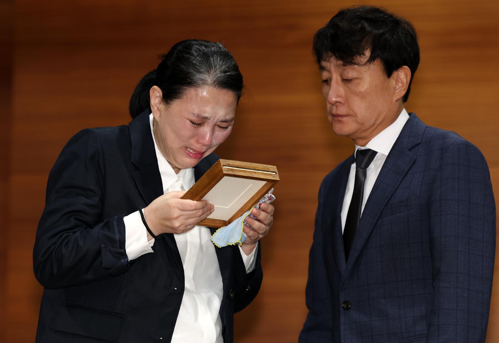 고 오요안나씨 어머니 장연미씨가 15일 오전 서울 마포구 MBC에서 열린 고 오요안나 1주기 관련 대국민 기자회견에서 안형준(오른쪽)  MBC 사장에게 명예사원증을 전달 받은 후 슬퍼하고 있다. 2025.10.15. 뉴시스