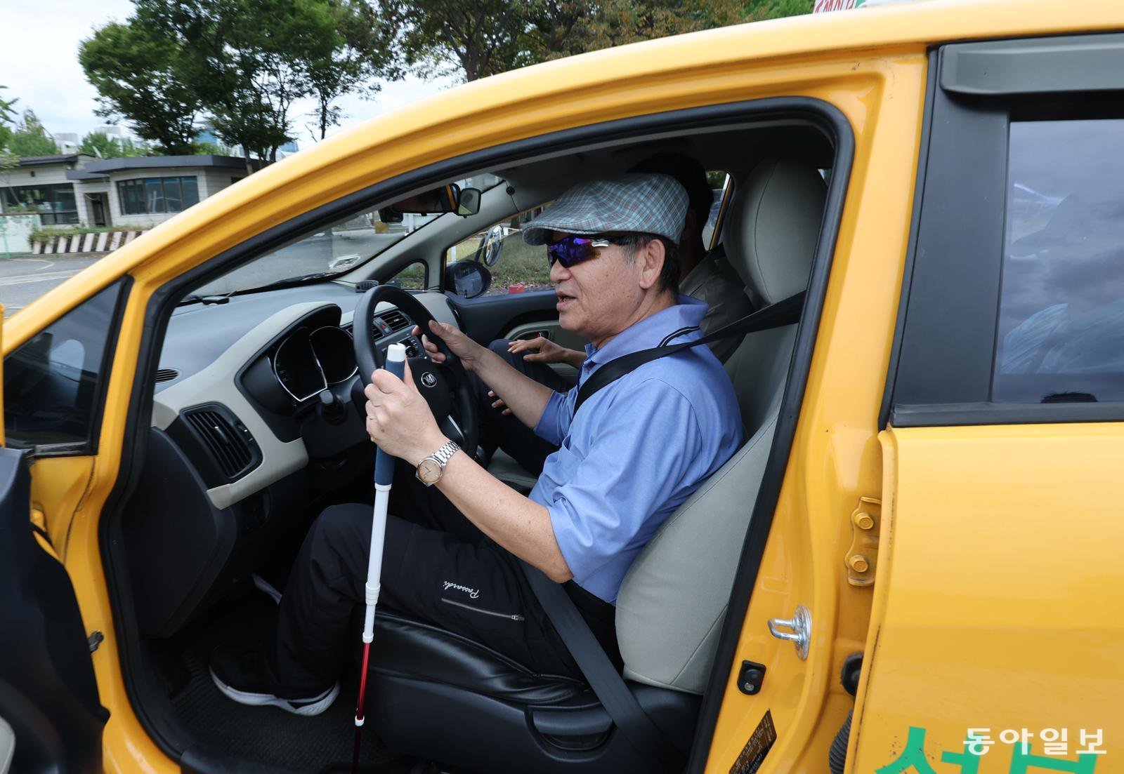 15일 서울 마포구 서부운전면허시험장 장내 기능 시험장에서 시각장애인 민희홍 씨(66)가 주행 체험을 하기 위해 시험용 차량 운전대를 잡고 있다. 실로암시각장애인복지관과 서부운전면허시험장은 이날 ‘흰 지팡이의 날’을 맞아 시각장애인 운전 체험 행사를 열었다. 홍진환 기자 jean@donga.com