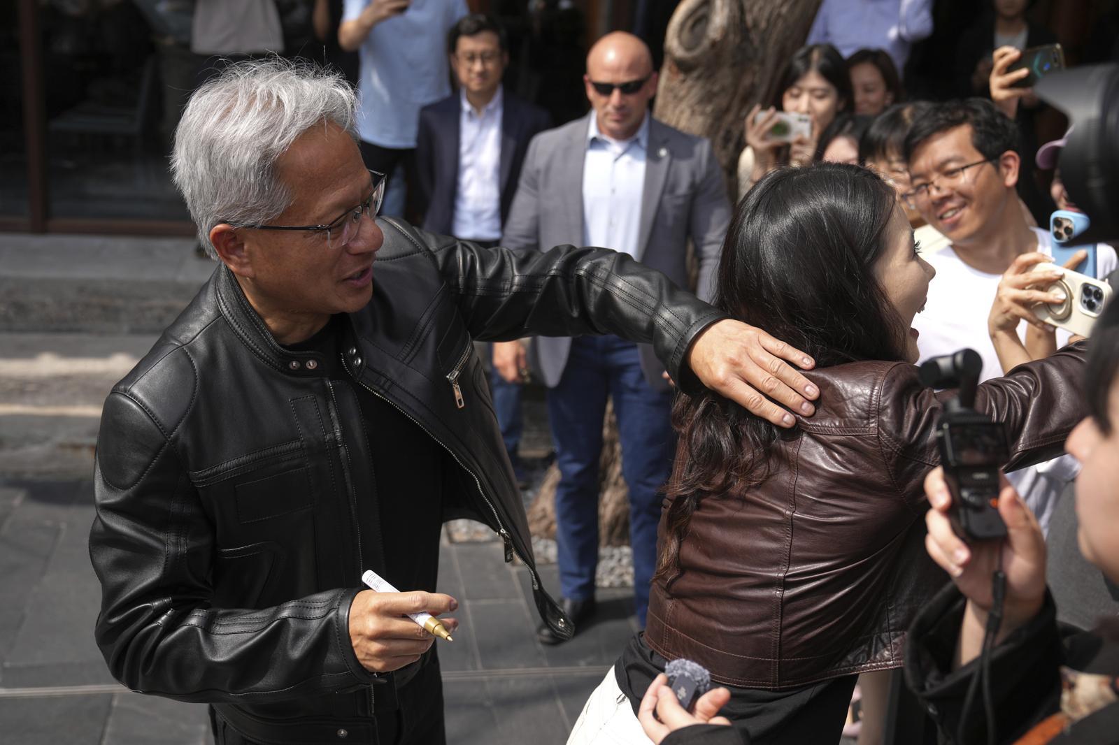 가죽 자켓을 즐겨입는 젠슨 황 엔비디아 최고경영자(CEO)가 한 기자의 가죽 자킷에 사인을 해주고 있다. (출처=AP/뉴시스)