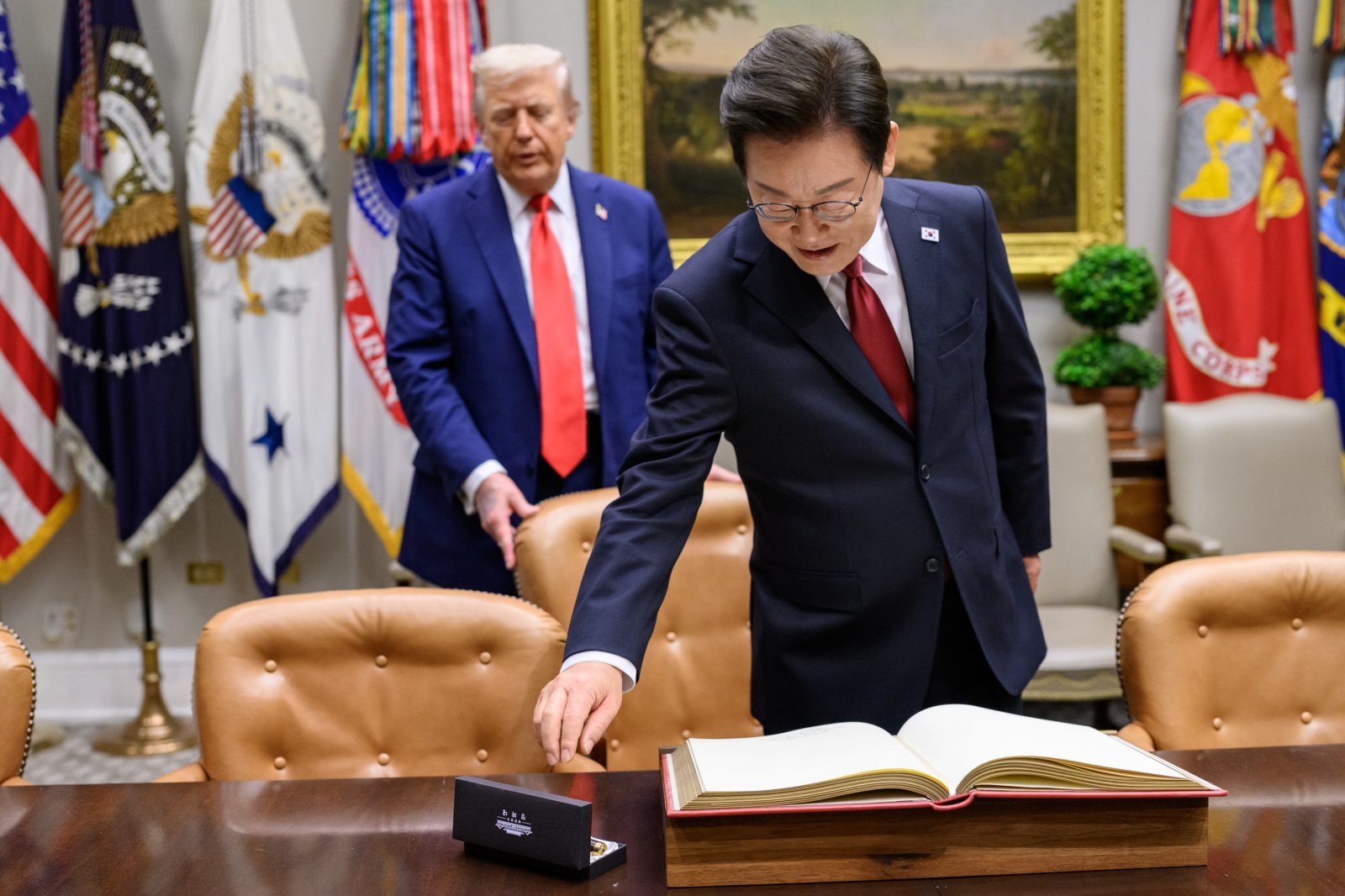 지난 8월 25일(현지시간) 이재명 대통령이 한미 정상회담에 앞서 미 백악관 루즈벨트룸에서 방명록에 서명하려고 펜을 잡으려는 순간 도널드 트럼프 미국 대통령이 뒤에서 의자를 당겨 주고 있다. 2025.9.1 백악관 제공