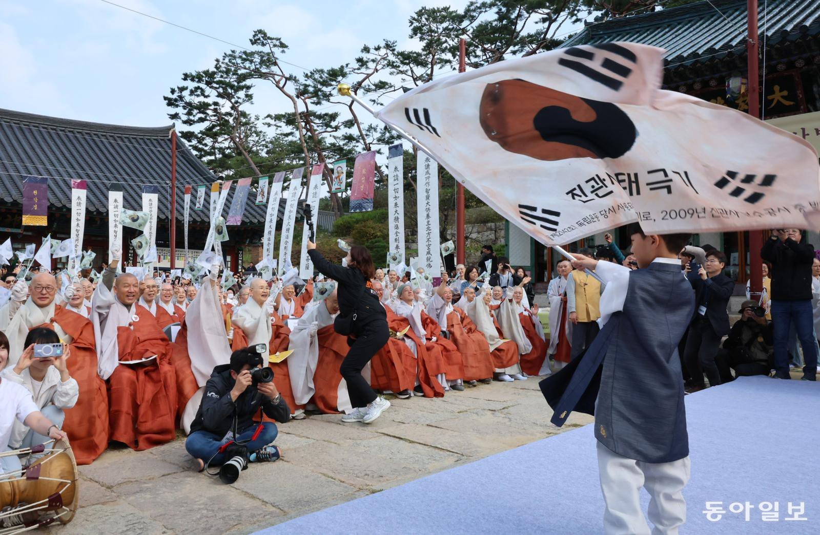 25일 서울 은평구 진관사에서 국행수륙재 개건 627주년을 기념해 열린 ‘2025년 진관사 수륙재’ 회향식에서 대웅전 야단법석에 참석한 한 어린이가 태극기를 흔들자 참가자들이 광복 80주년을 맞아 만세 삼창을 외치고 있다. 전영한 기자 scoopjyh@donga.com