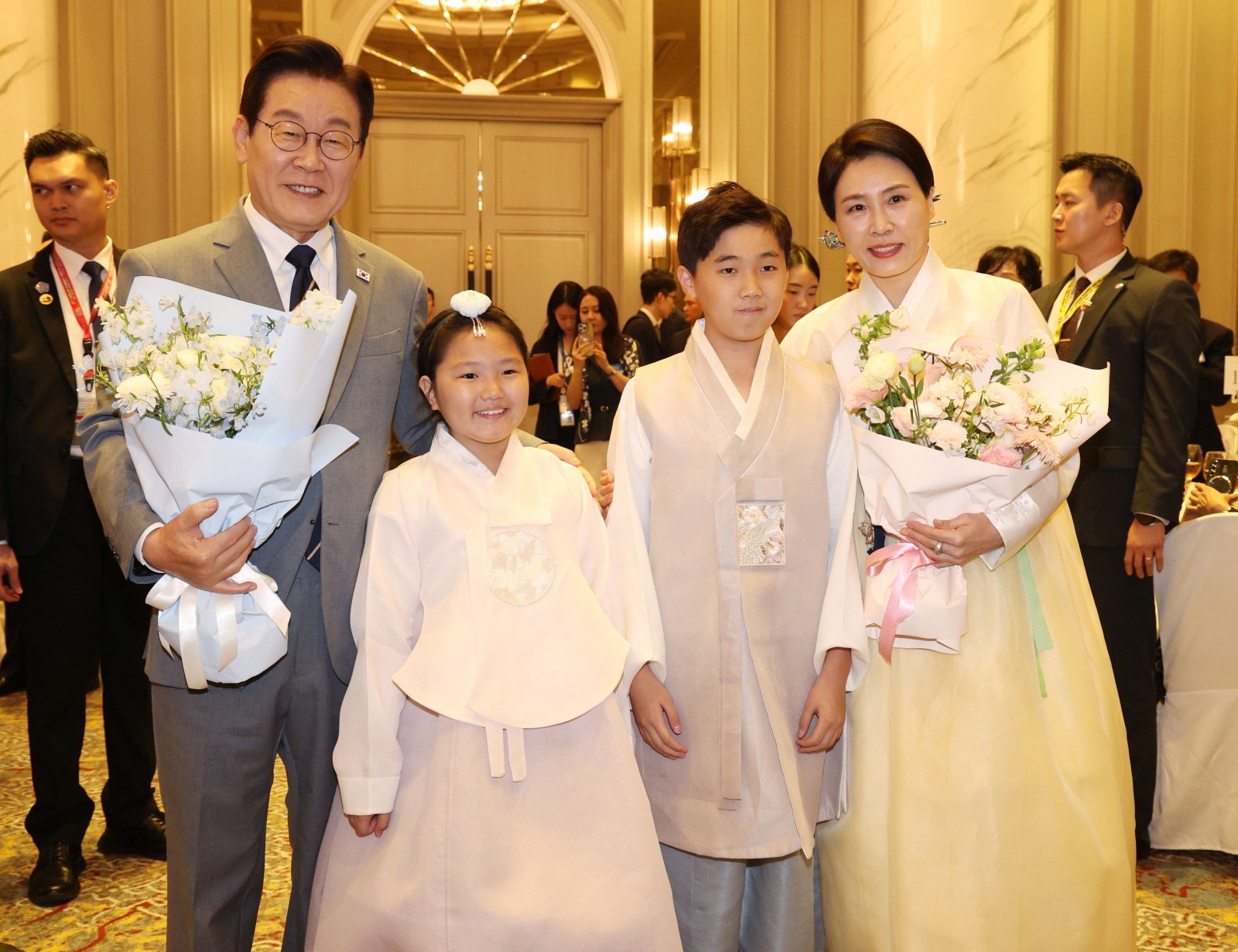 이재명 대통령과 김혜경 여사가 26일(현지 시간) 말레이시아 쿠알라룸푸르 한 호텔에서 열린 동포 간담회에서 화동에게 꽃다발을 받은 뒤 함께 기념촬영을 하고 있다. 뉴시스