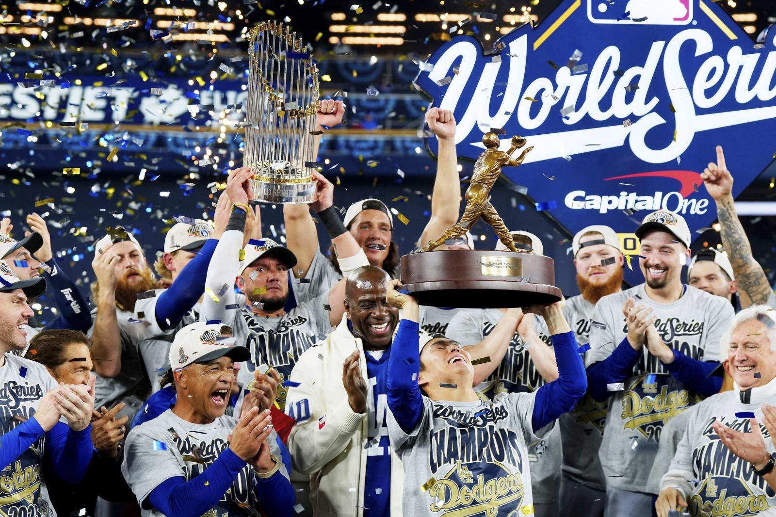 야마모토 요시노부(왼쪽에서 세 번째)가 2025 미국프로야구 메이저리그 월드시리즈 7차전 승리 후 열린 시상식에서 최우수선수(MVP)로 선정된 뒤 동료들의 축하 속에 트로피를 머리 위로 들어올리고 있다. 데이브 로버츠 다저스 감독과 매직 존슨 구단주도 환한 미소로 축하의 박수를 보내고 있다. 토론토=AP 뉴시스