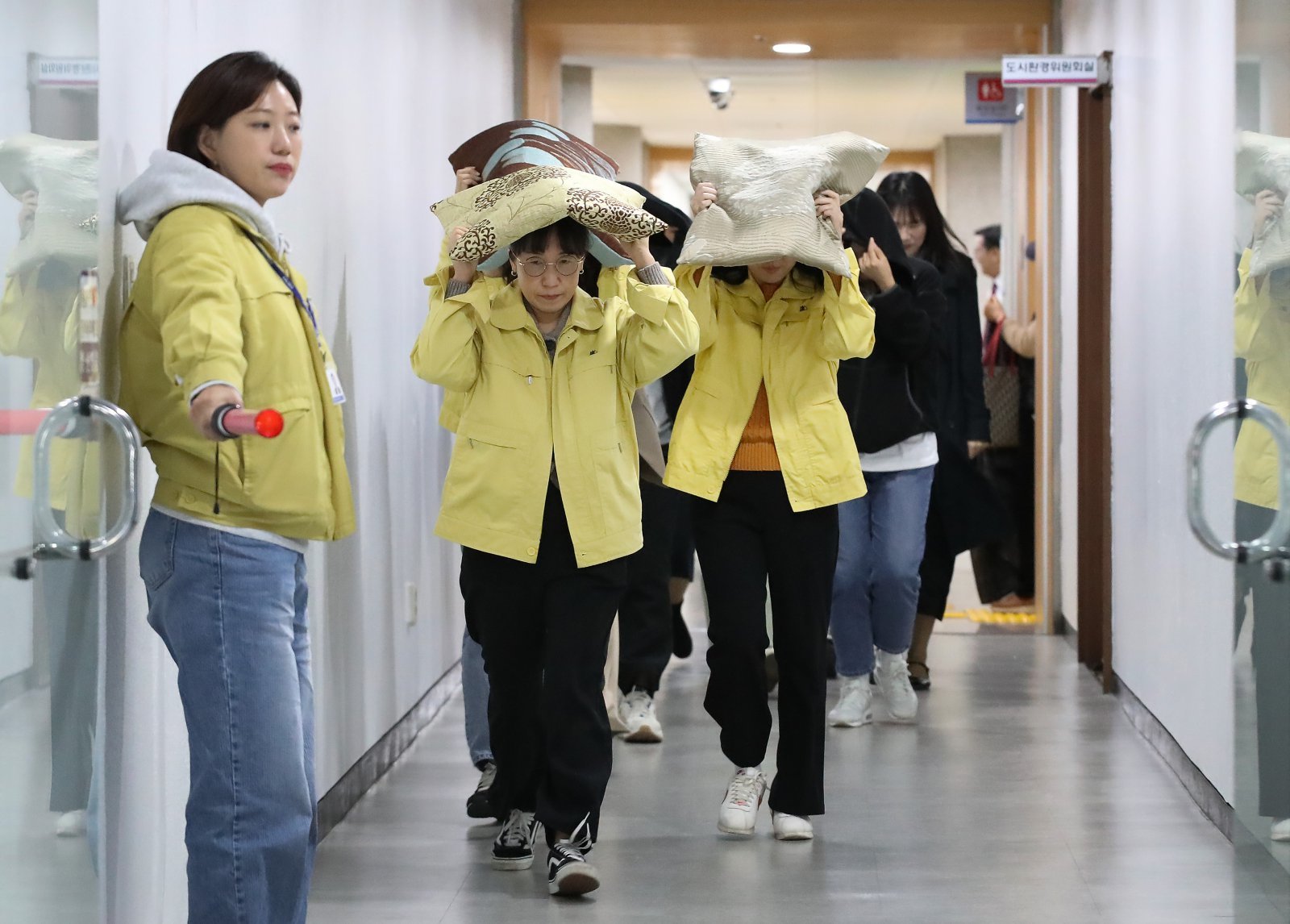대구 달서구청에서 지진 발생 상황을 가정해 열린 대피 훈련에서 구청 직원들이 지진 대피 안내방송에 따라 방석으로 머리를 보호하며 인근 대피소로 이동하고 있다. 2025.10.28/뉴스1