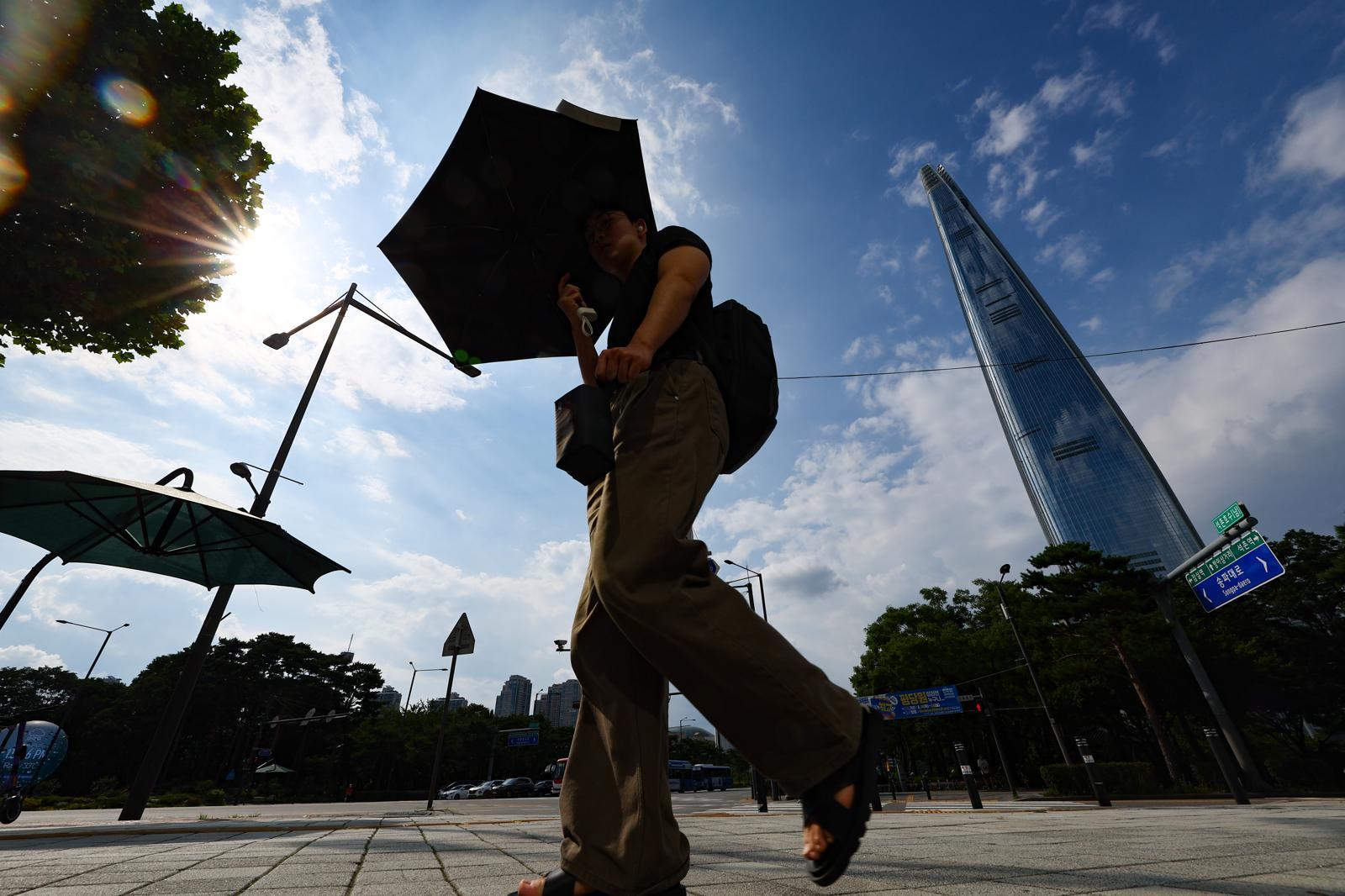 폭염경보가 발효된 8월 서울 송파구 석촌호수 사거리에서 양산을 쓴 시민들이 발걸음을 옮기고 있다. 사진=뉴시스