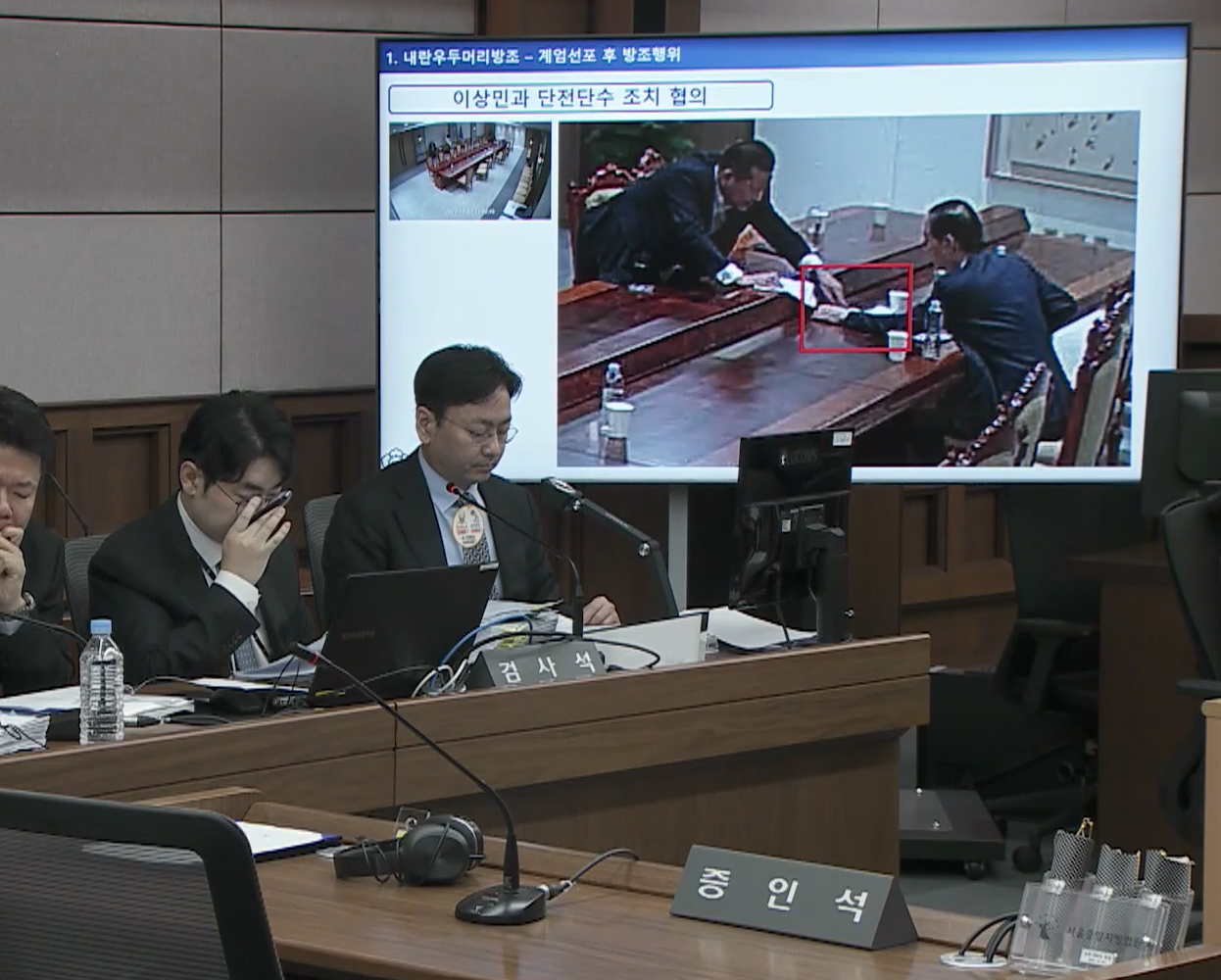 2025년 10월 13일 서울중앙지법 형사합의33부(부장판사 이진관) 심리로 열린 한덕수 전 국무총리 2차 공판에서 특검이 제시한 12·3 비상계엄 당일 대통령실 폐쇄회로(CC)TV 영상 화면에 한 전 총리(오른쪽)와 이상민 전 행정안전부 장관이 계엄 관련 문건을 주고받고 있는 모습이 재생되고 있다. 법원 공판 중계 화면 캡처